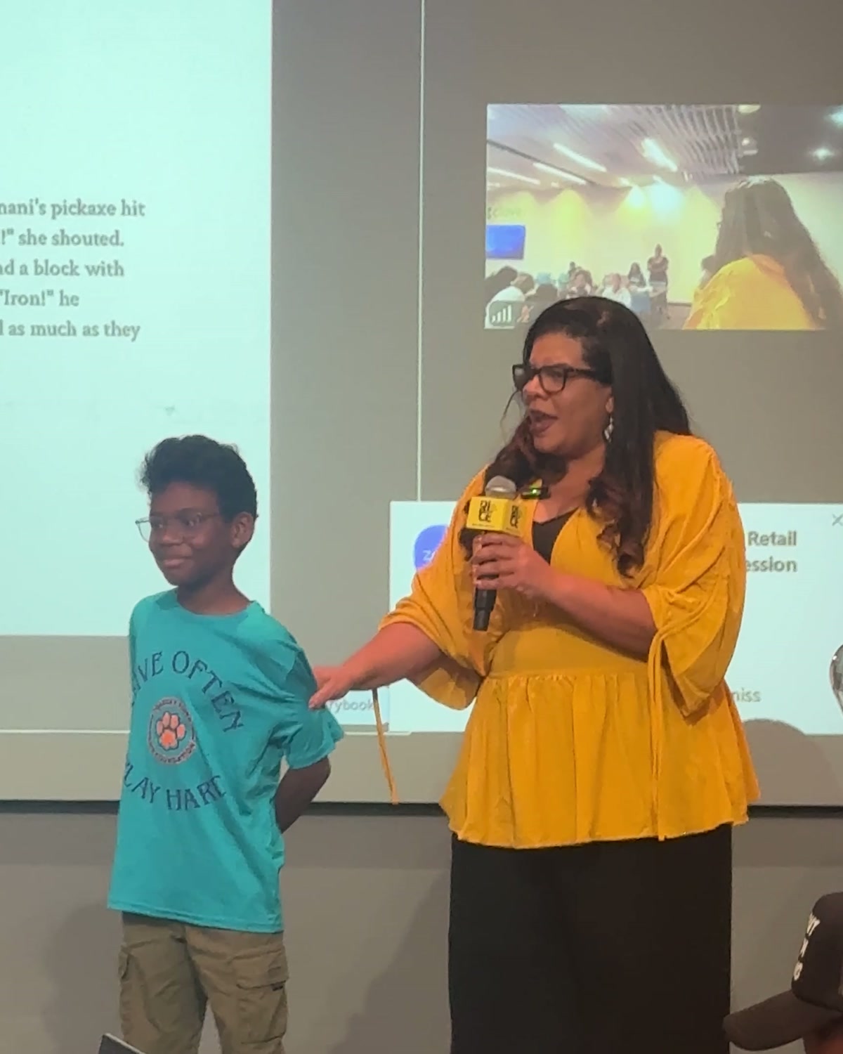 A child speaking into a microphone beside a projected AI-generated storybook page