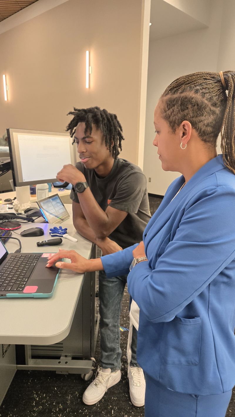 An instructor guiding a youth intern through an exercise on a laptop during the TAG-Ed AI Boot Camp