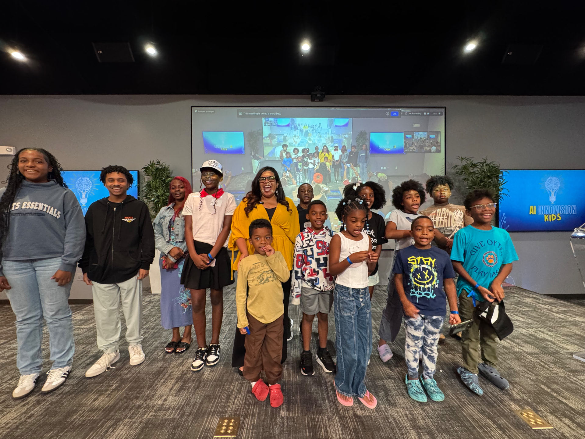 Children and facilitators smiling together in front of screens displaying the AI InnoVision Kids logo